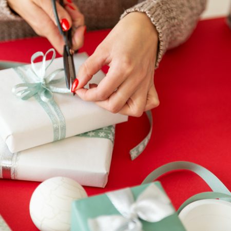 DIY Gift Wrapping. Unrecognisable woman wrapping beautiful nordic style christmas gifts. Hands close up.
